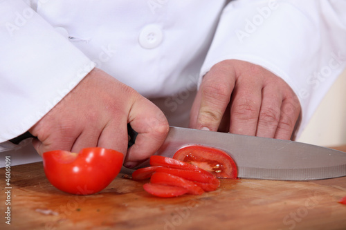Photo: A cook slicing a tomato A cook slicing a tomato