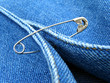 Photo: blue denim clothes fragment with safety pin blue denim clothes fragment with safety pin