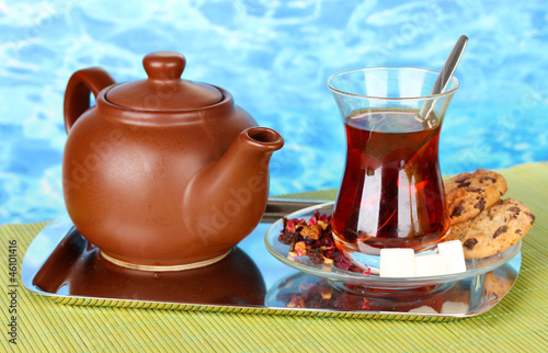 Photo: glass of Turkish tea and kettle on color background glass of Turkish tea and kettle on color background