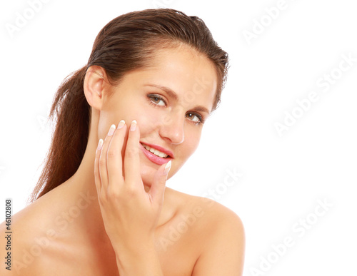 Photo: A beautiful woman is applying cream on her face over white A beautiful woman is applying cream on her face over white