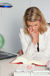 Foto: Frau am Schreibtisch liest in Buch Frau am Schreibtisch liest in Buch
