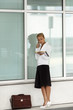 woman holding file speaking on telephone near office building