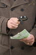 Hand with euro banknotes and magnifier