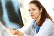 A female doctor is examining x-ray of a chest at the desk