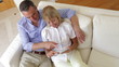 Senior Couple Sitting On Sofa Using Digital Tablet