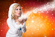 junge blonde Frau im Winteroutfit pustet Schnee