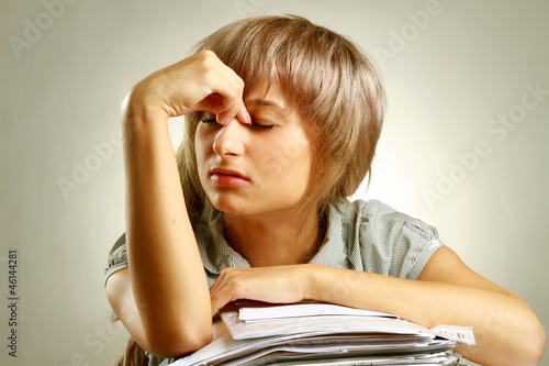 Photo: A tired young woman sitting at the desk A tired young woman sitting at the desk
