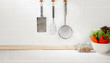 Kitchen cooking utensils on hook against tile wall