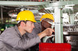 two textile weaving machine mechanics repairing loom