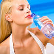 Foto: Woman with bottle of water on beach Woman with bottle of water on beach
