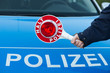 Polizist hält kelle vor Polizeiauto