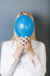 frau mit luftballon vor grauer wand