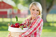 A Young Blonde Woman Holding a Basket of Apples