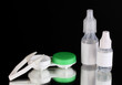 Eye drops and lenses on black background