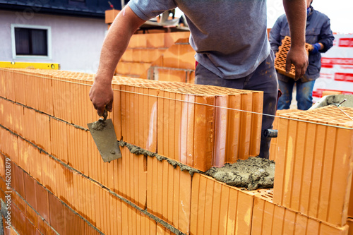 Photo: Maurer mit Ziegelmauer auf Baustelle Maurer mit Ziegelmauer auf Baustelle