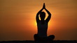 Healthy woman meditating in pose lotus over orange sun