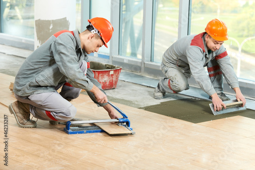 Photo: Two tilers at industrial floor tiling renovation Two tilers at industrial floor tiling renovation