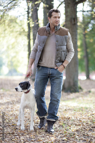 Photo: Mann geht mit Hund an einem Herbsttag spazieren Mann geht mit Hund an einem Herbsttag spazieren