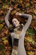 Beautiful young woman laying in fallen leaves.