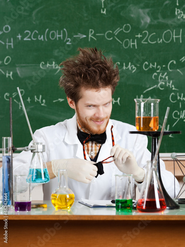 Photo: Mad professor rubs his glasses while working in his laboratory Mad professor rubs his glasses while working in his laboratory