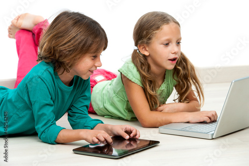 Photo: Two kids on floor with laptop and tablet. Two kids on floor with laptop and tablet.