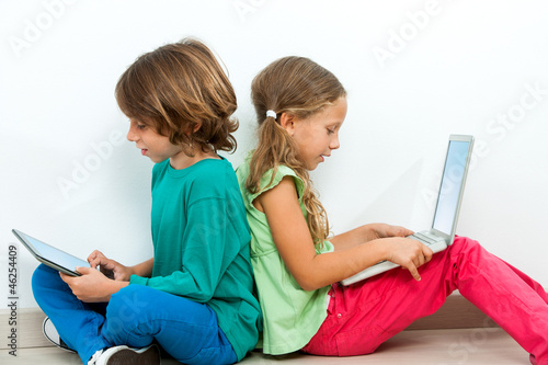 Photo: Two kids socializing with laptop and tablet. Two kids socializing with laptop and tablet.