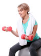 Cute mid aged women with towel do exercises with dumbbells
