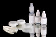 Eye drops and lenses on black background
