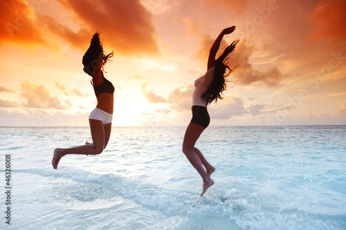 Photo: Two happy women jumping on beach Two happy women jumping on beach