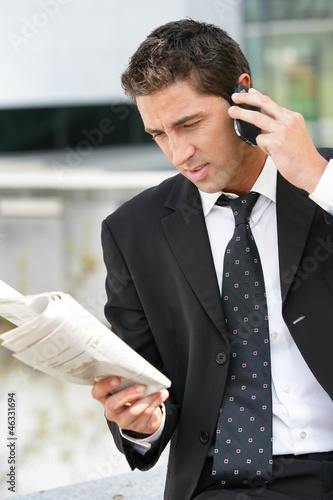 Photo: Businessman with phone and newspaper Businessman with phone and newspaper