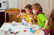 Photo: Two little girls (sisters) painting on Easter eggs Two little girls (sisters) painting on Easter eggs