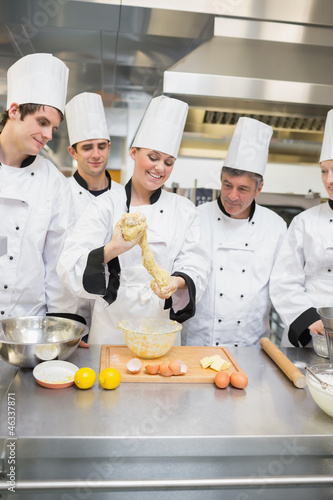 Photo: Smiling pastry teacher showing class how to form dough Smiling pastry teacher showing class how to form dough