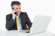 Foto: Happy man phoning while typing on laptop Happy man phoning while typing on laptop