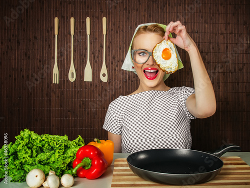 Photo: Happy funny woman cook holding pan with fried egg - close up Happy funny woman cook holding pan with fried egg - close up