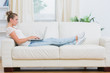 Photo: Blond woman looking at the laptop on the couch Blond woman looking at the laptop on the couch