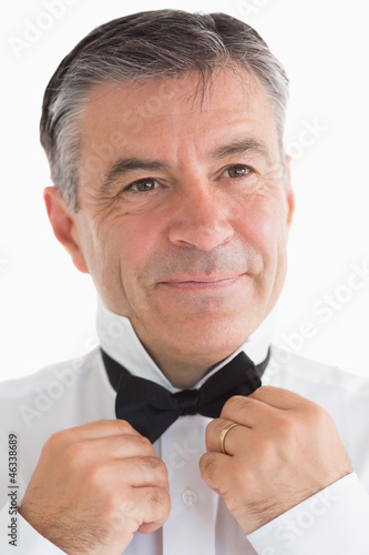 Photo: Happy man adjusting his bow tie Happy man adjusting his bow tie
