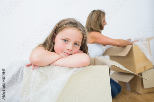 Photo: Daughter sitting in the box while her mother unpacking something Daughter sitting in the box while her mother unpacking something