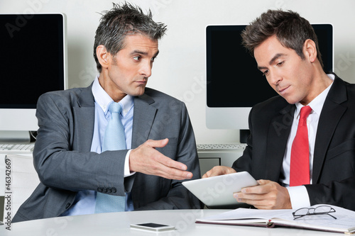 Photo: Businessmen Using Digital Tablet At Desk Businessmen Using Digital Tablet At Desk