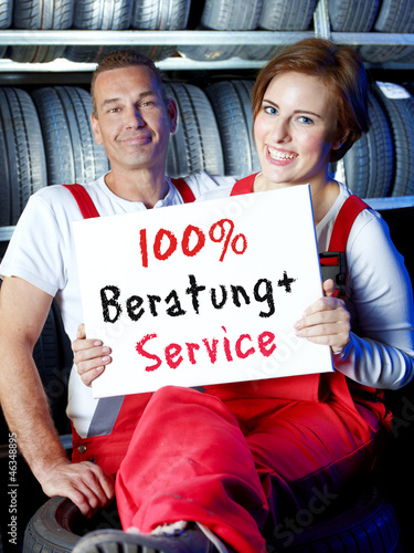 Photo: Woman showing blackboard with 100 % service and consulting Woman showing blackboard with 100 % service and consulting