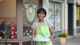 Video: Proud African American coffee shop owner in apron holding tray with coffee cups outside cafe Proud African American coffee shop owner in apron holding tray with coffee cups outside cafe