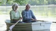 Smiling Caucasian couple rowing boat on river
