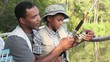 Black father and son adjusting reel on fishing rod