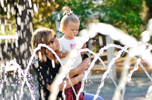 Photo: mother and daughter playing with fountain mother and daughter playing with fountain