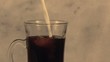 Close up of cream pouring into coffee (slow motion)