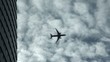 Airplane flying past building with clouds in the background