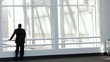 Black businessman walks to window, looks out and leaves