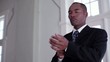Mixed race businessman in community hall fixing tie and adjusting cuffs while waiting