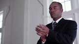 Video: Mixed race businessman in community hall fixing tie and adjusting cuffs while waiting Mixed race businessman in community hall fixing tie and adjusting cuffs while waiting