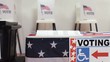 Registration table and ballot box with voting booths in the background
