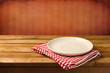 Empty white plate on wooden table over red grunge background